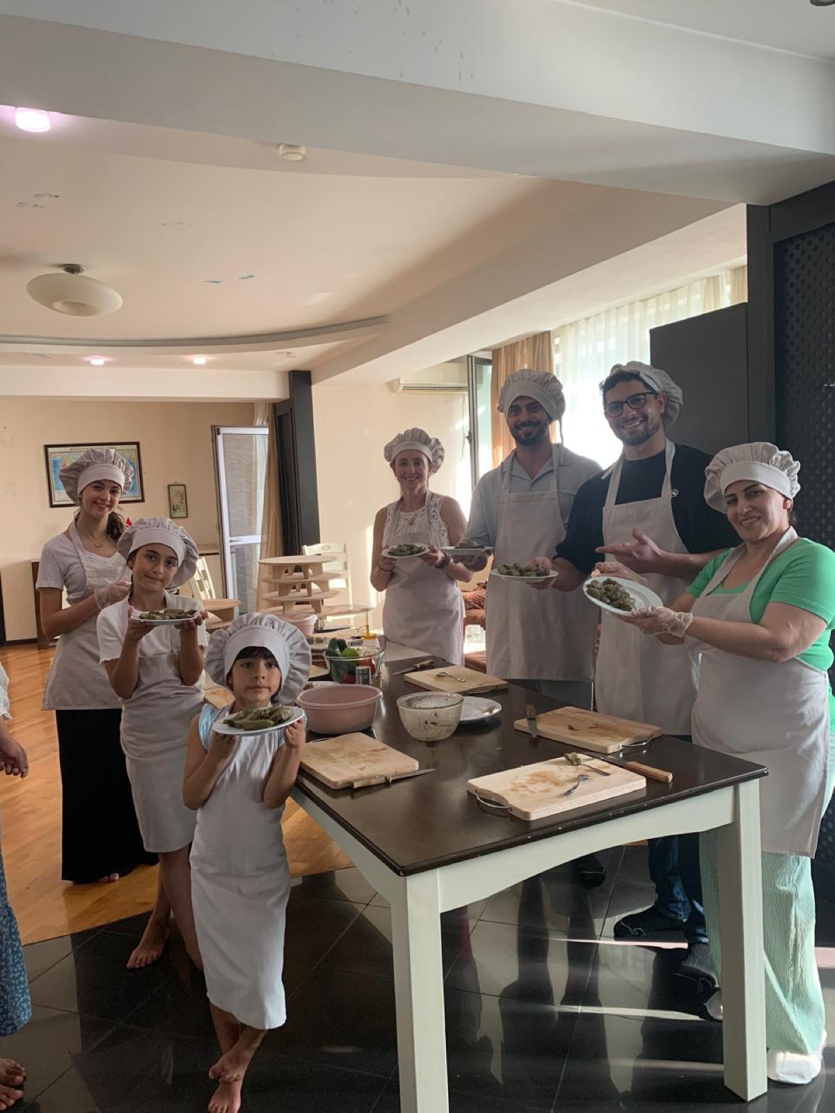 Family group showing dolma plates during a cooking class in Baku